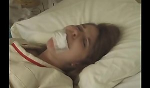 Pretty brunette in Straight-jacket taped mouth forced tied beside bed hospital